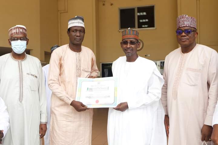 Minister of the FCT, Muhammad Musa Bello (m) receives certificate from the principal of GSS Kubwa, who emerged as the overall winner as the best School Administrator during the celebration of world Teachers Day.