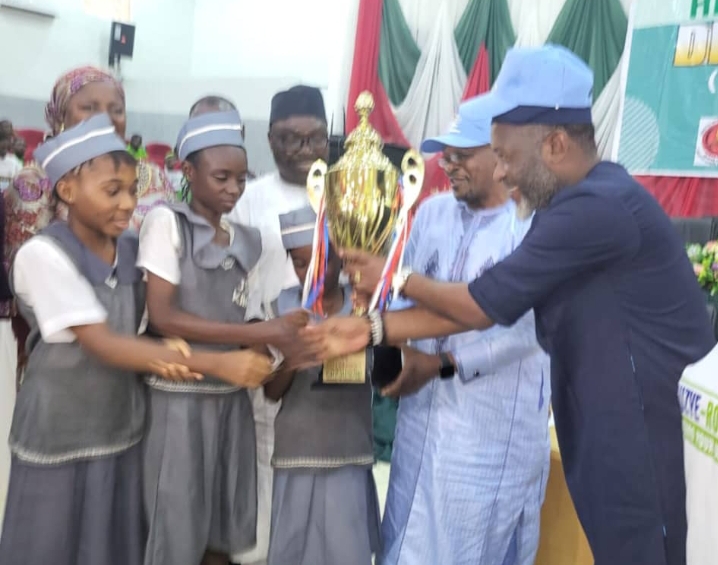 The FCT director of UBEB, Dr Hassan Sule second right present trophy to students of JSS Karu, after they emerged winner of the quiz/debate competition in Abuja.