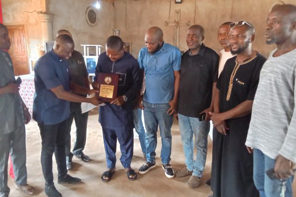 Comrade Benjamin Jeremiah Ojodale, Chairman of the National Youth Council of Nigeria, Kogi State chapter (M) holding the award presented to him, supported by Hon Destiny Keller, the SSA on Youth Mobilisation and NYCN Coordinators from Eastern region of Kogi State