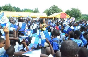 Dr. Betta Edu distributing school materials to children 