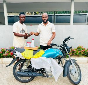 Hon. Oladele John Nihi, Special Adviser on Youth & Student Affairs to the Kogi State Governor (R) presenting a brand new motorcycle to Mr. Oloruntoba Victor Dele, from Ila community in Bunu, Kabba-Bunu LGA of Kogi State
