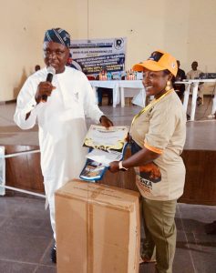 Hon. David Maiyaki, presenting teachers materials to one of the participants of the training.
