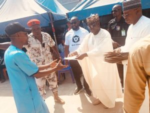 Hon. Baba Ali handing over cash to beneficiary.